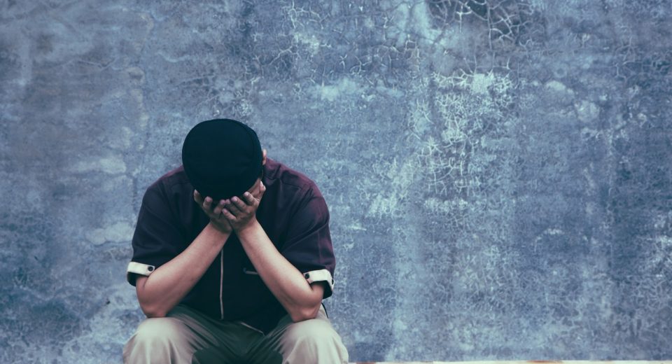 a man sitting on a bench with a black hat and headphones on